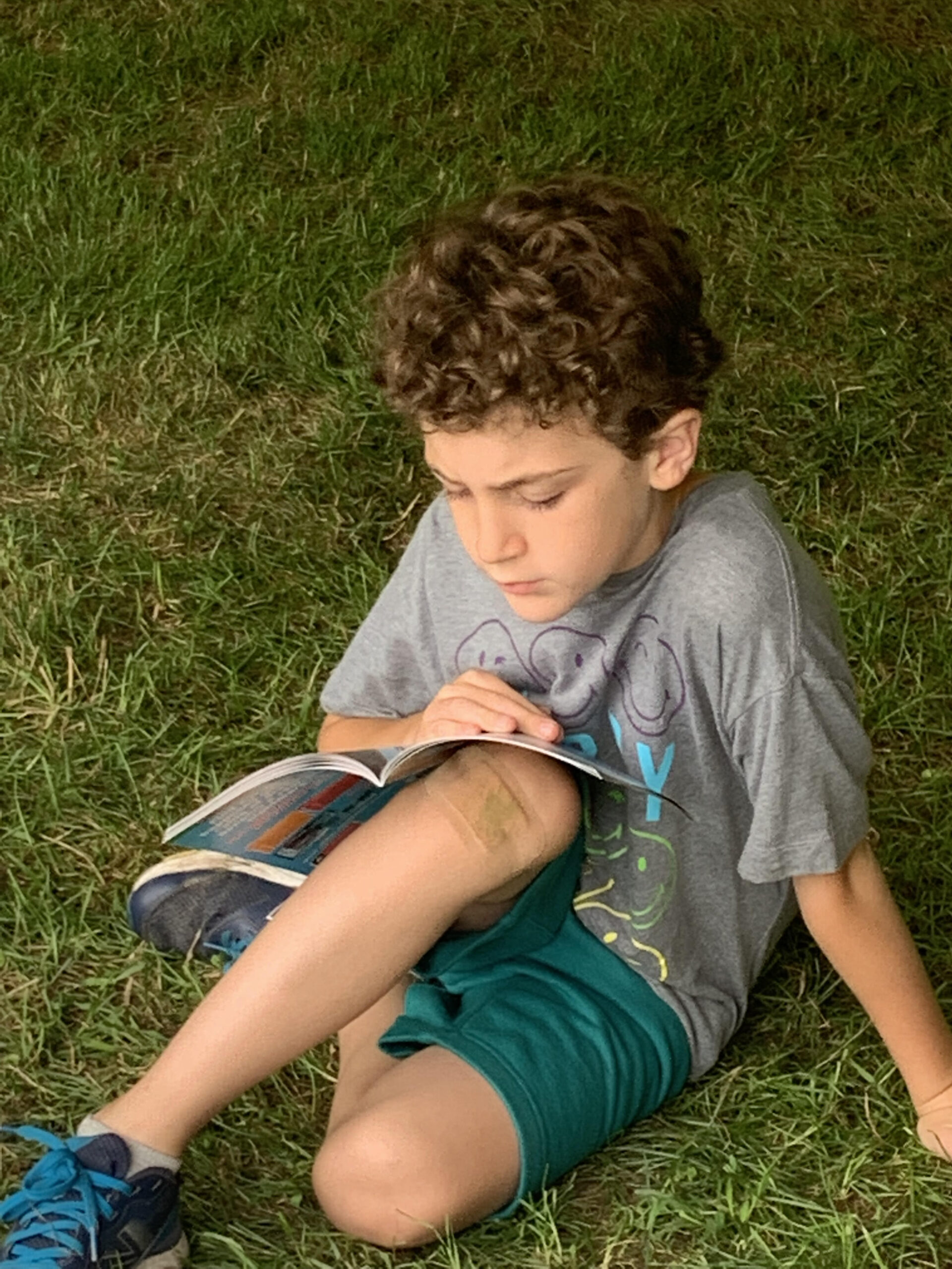 Child reading a book in the grass